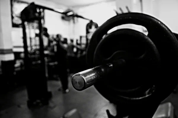 Barre chargée au premier plan dans une salle de sport